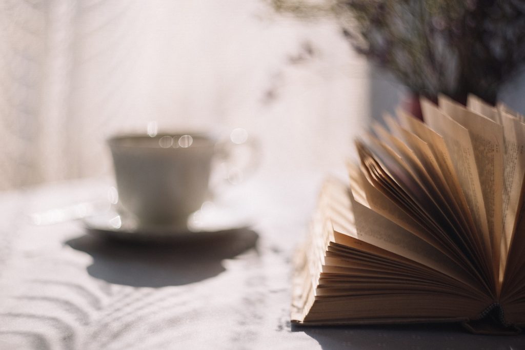 Ein geöffnetes Buch und eine Tasse im Hintergrund